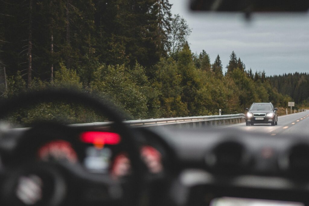 View from a car driving on a scenic road in Norway with a vehicle approaching.